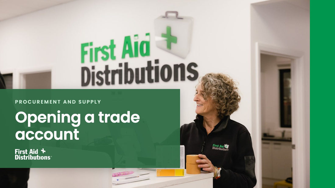 Opening a trade account: a smiling staff member at the First Aid Distributions front counter, in front of the company wall sign, First Aid Distributions